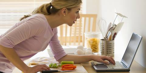 a woman in the kitchen checking her laptop for tips and tricks