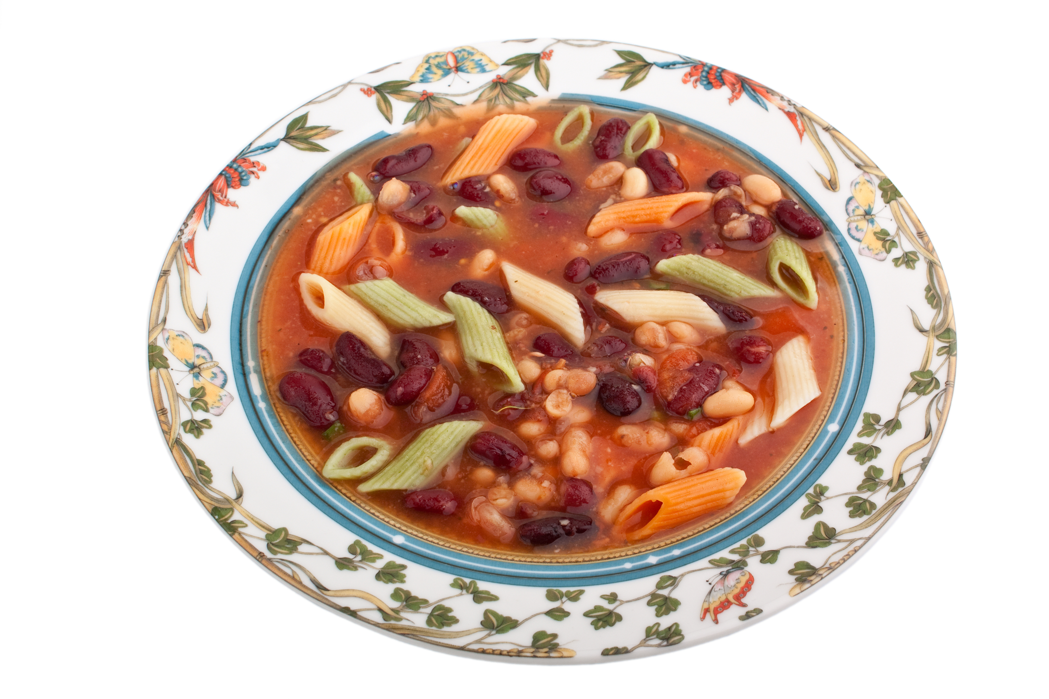 Colorful bowl of minestrone soup in a white bowl with floral decorative elements on rim.