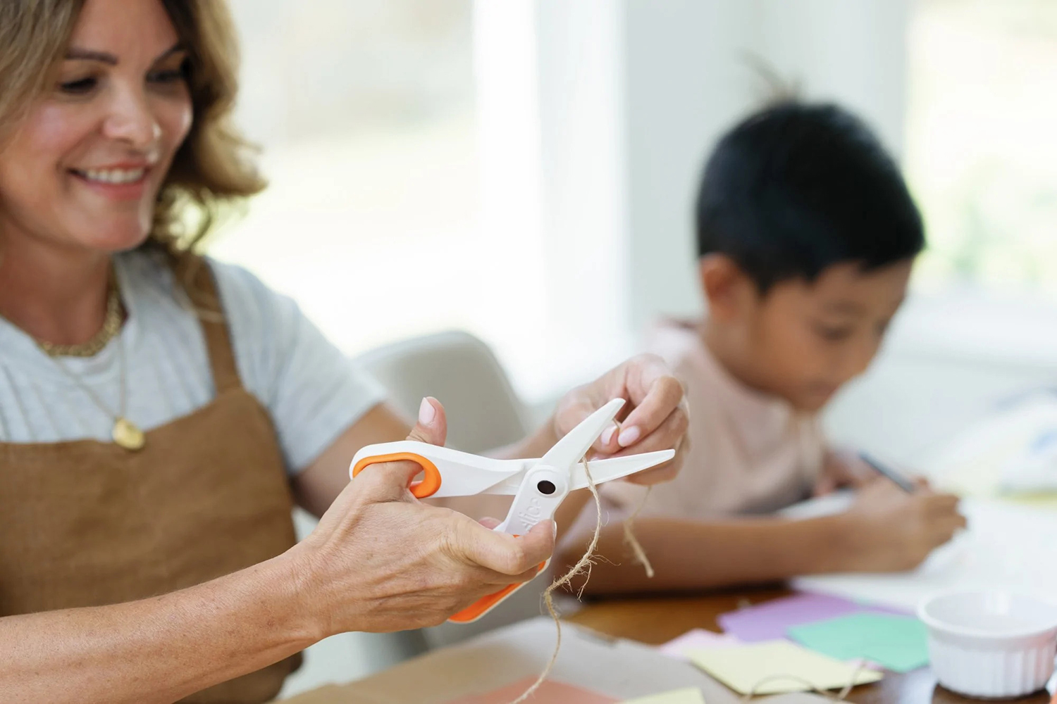 a mother using scissors to help her child with a craft project