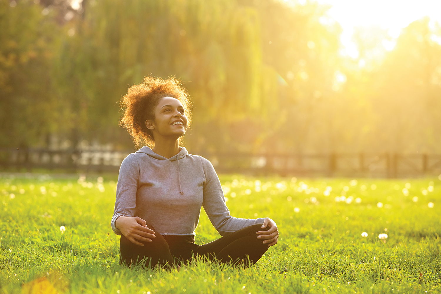 A woman sitting with legs crossed in a sunny field