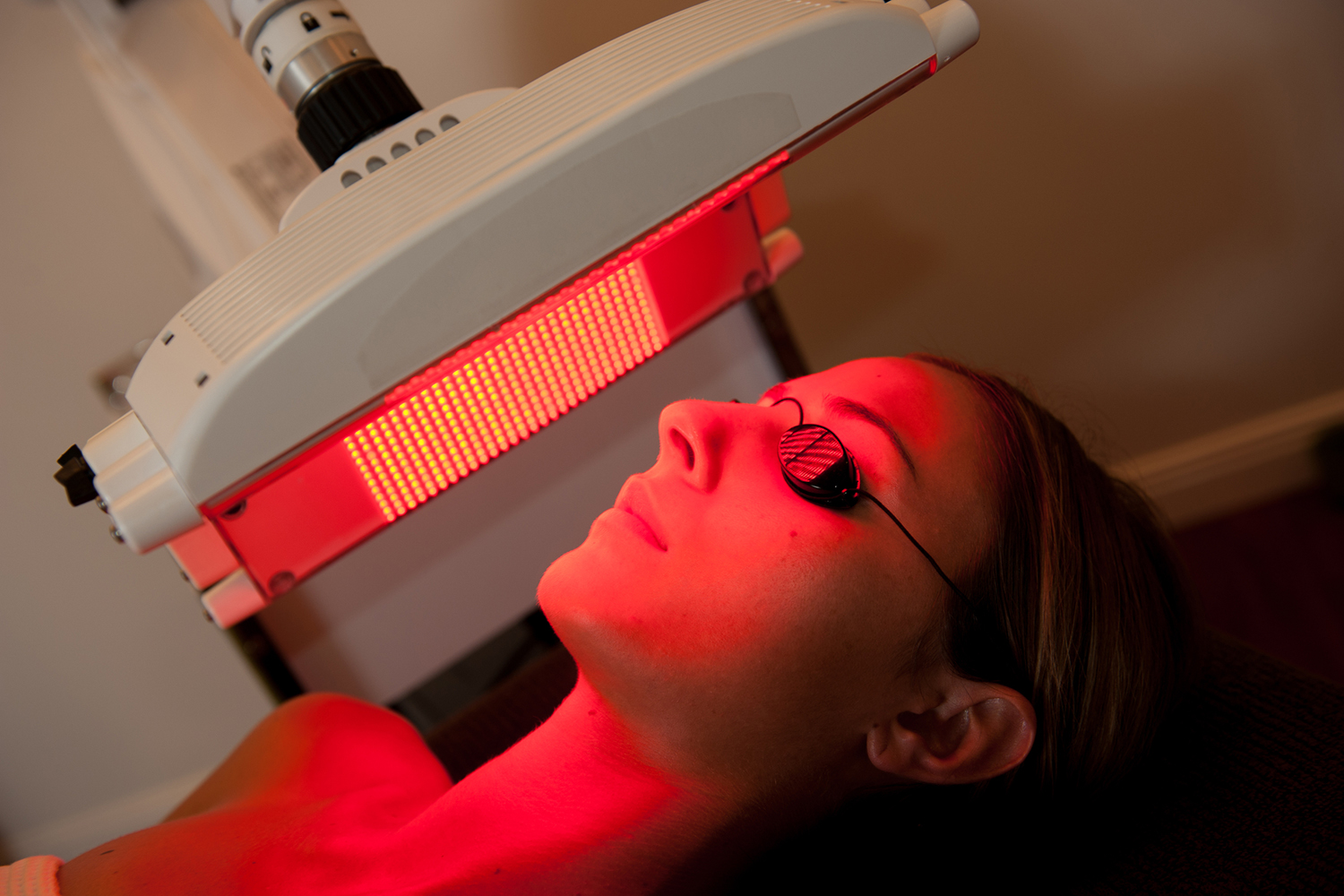 a woman having red light therapy applied to her face