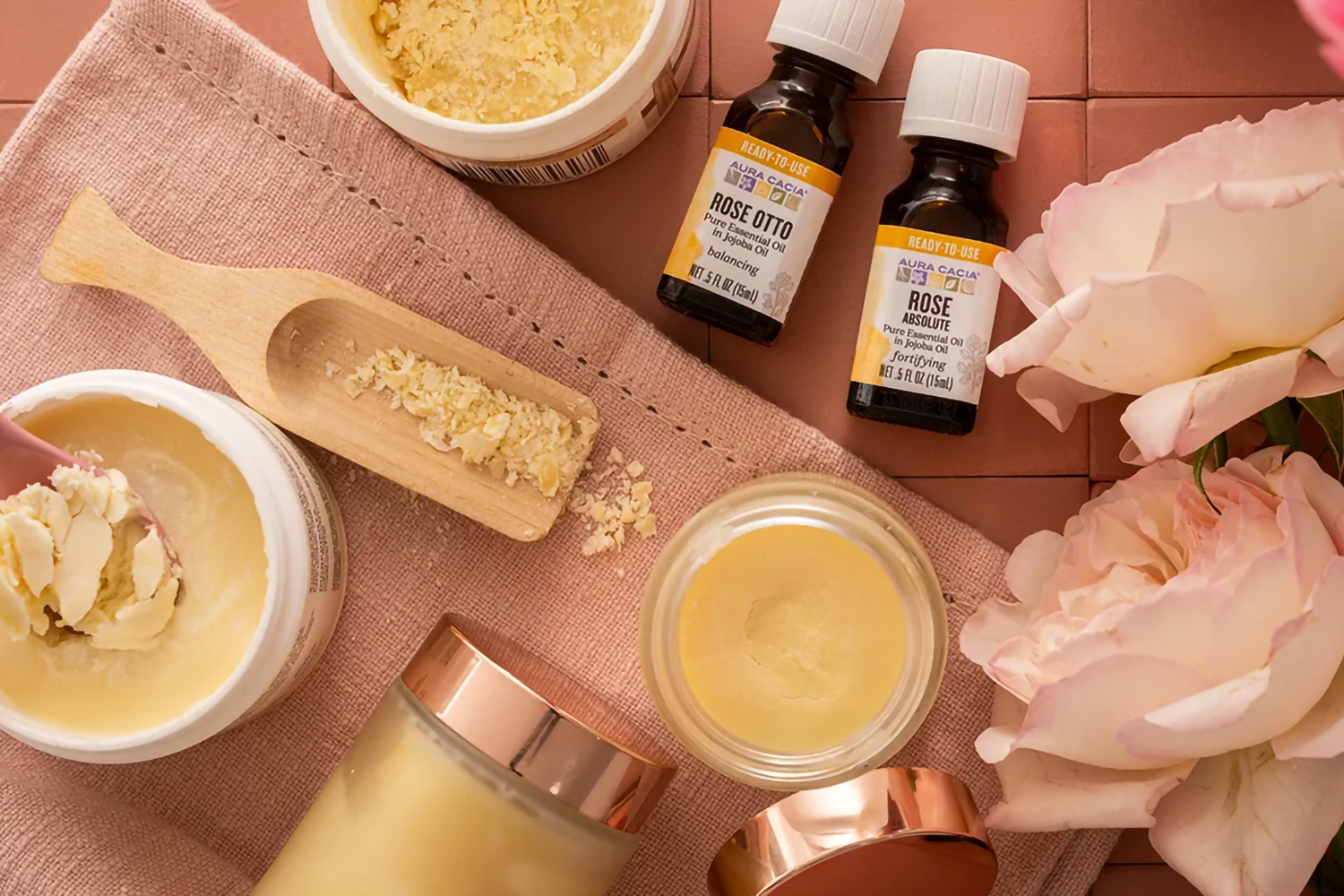 a tub of cocoa butter and bottles of rose essential oils