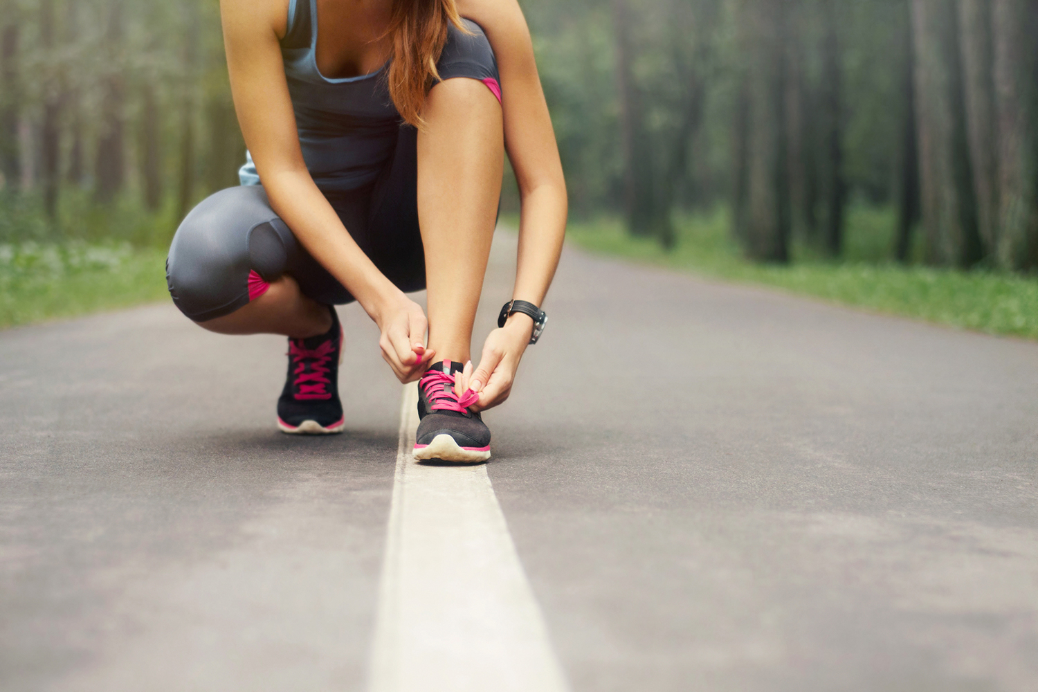 A woman tying her shoe in preparation for a run.