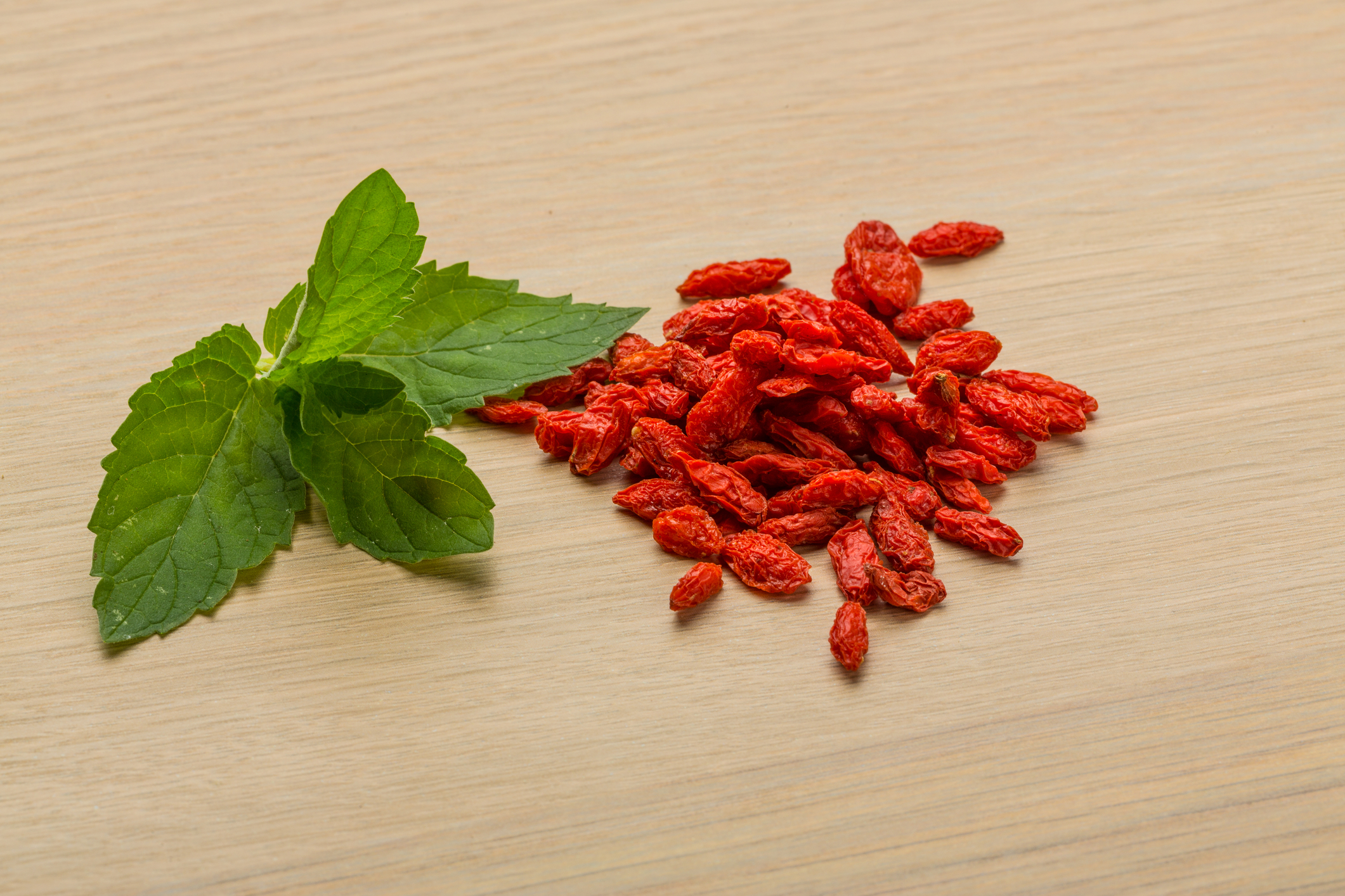 Bright red berberine next to a green leaf. 