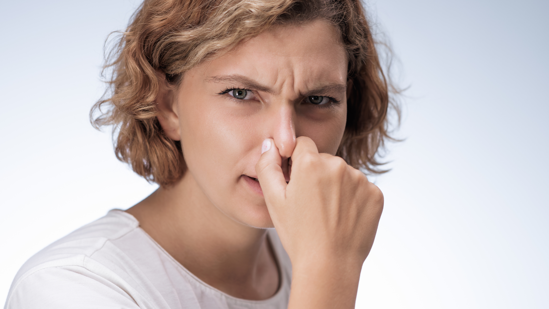 Woman holding her nose.