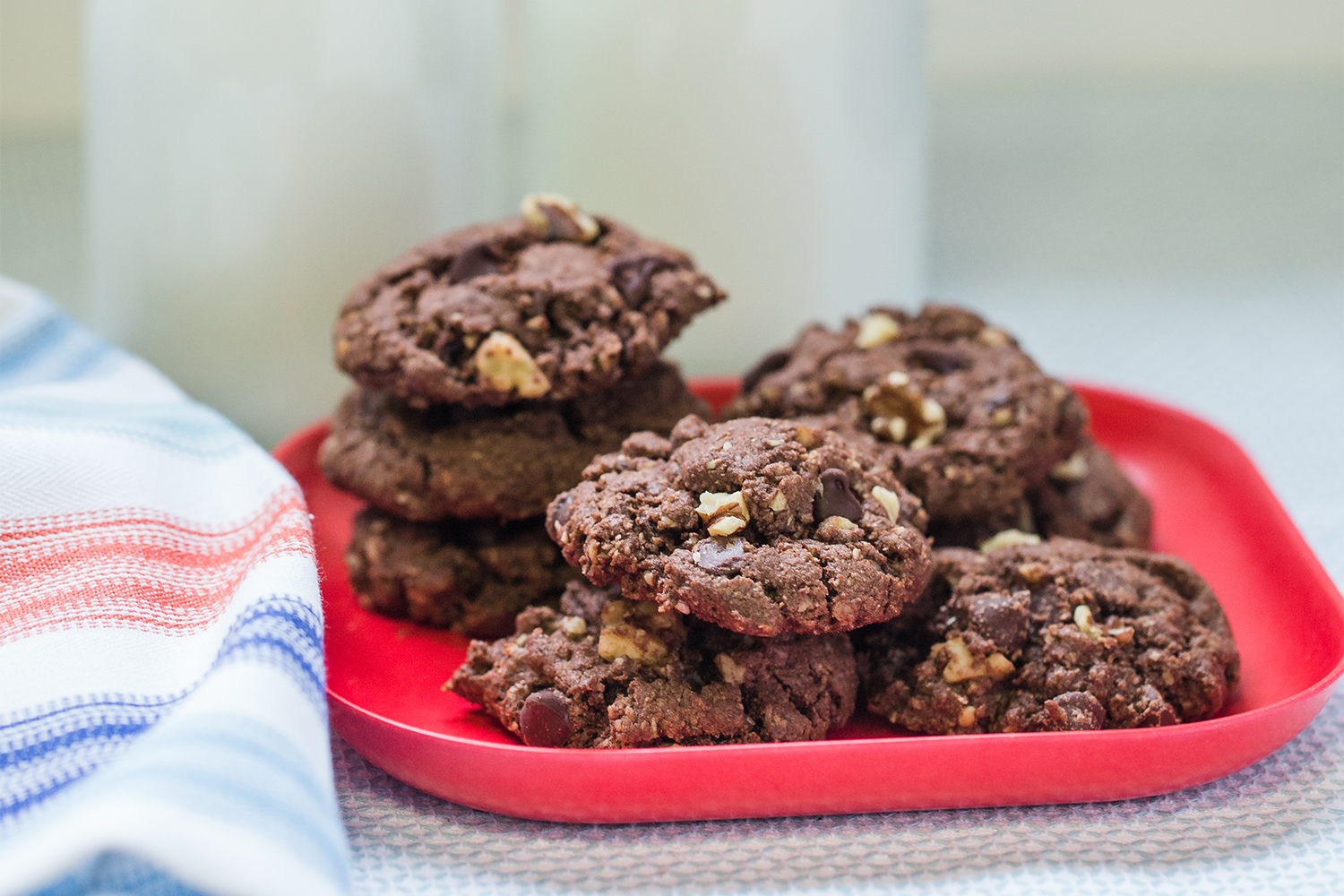 A plate of chocolate chip oatmeal cookies and two tall glasses of milk