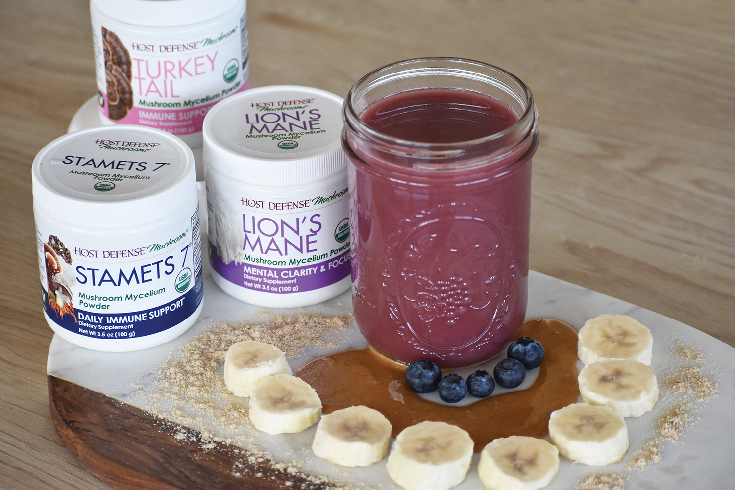 Paul Stamets' Signature Smoothie in a glass mason jar next to ingredients and Host Defense mushroom powders.