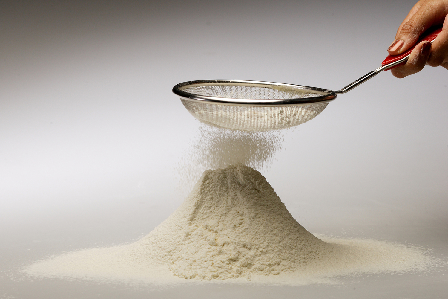 alternative flour falling from a sifter into a pile