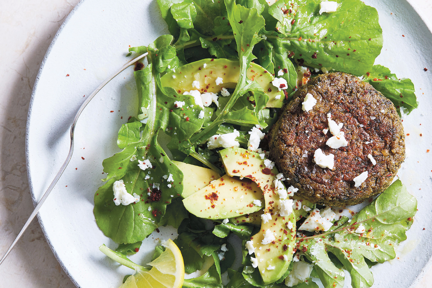 Lentil and Chard Cakes on white plate garnished with avocado.