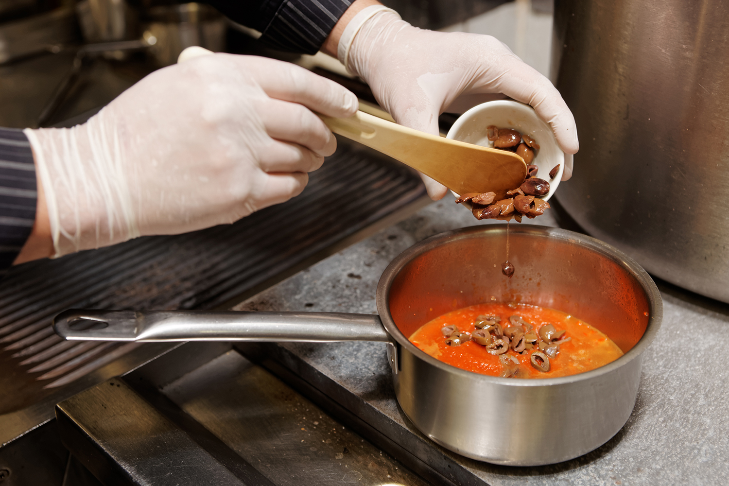 someone cooking a puttanesca sauce with chopped olives and minced anchovies