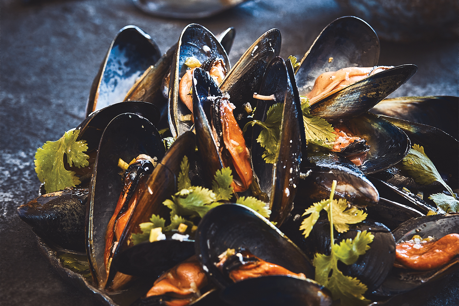 Grilled mussels served on a dark platter
