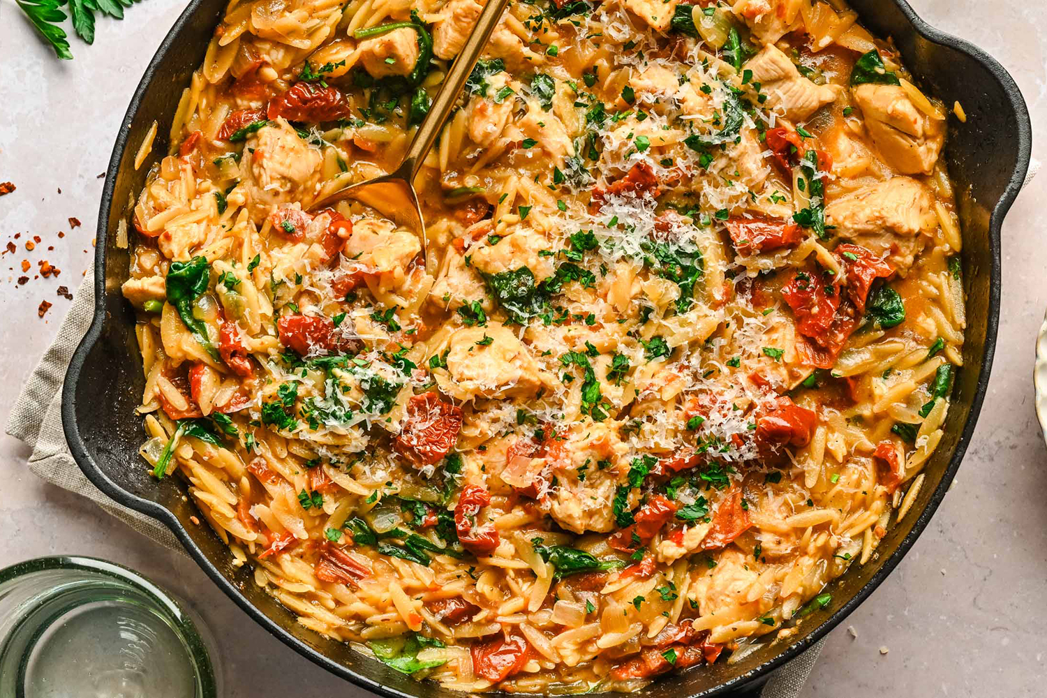 a pan of seasoned chicken with orzo and spinach
