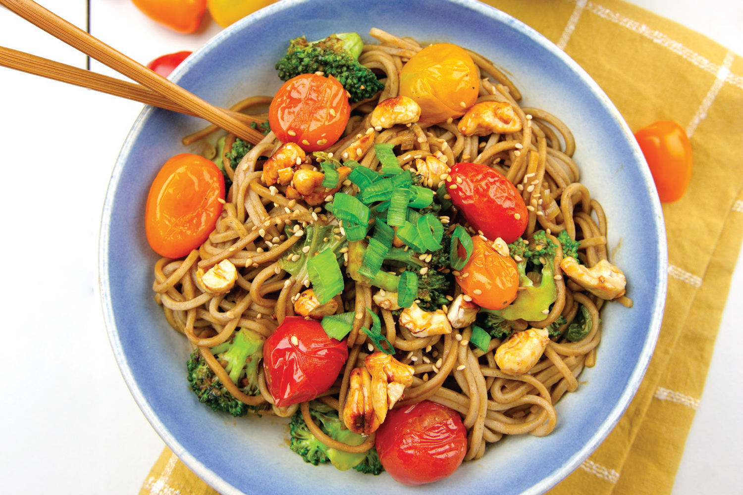 a bowl of noodles with cherry tomatoes and candied cashews