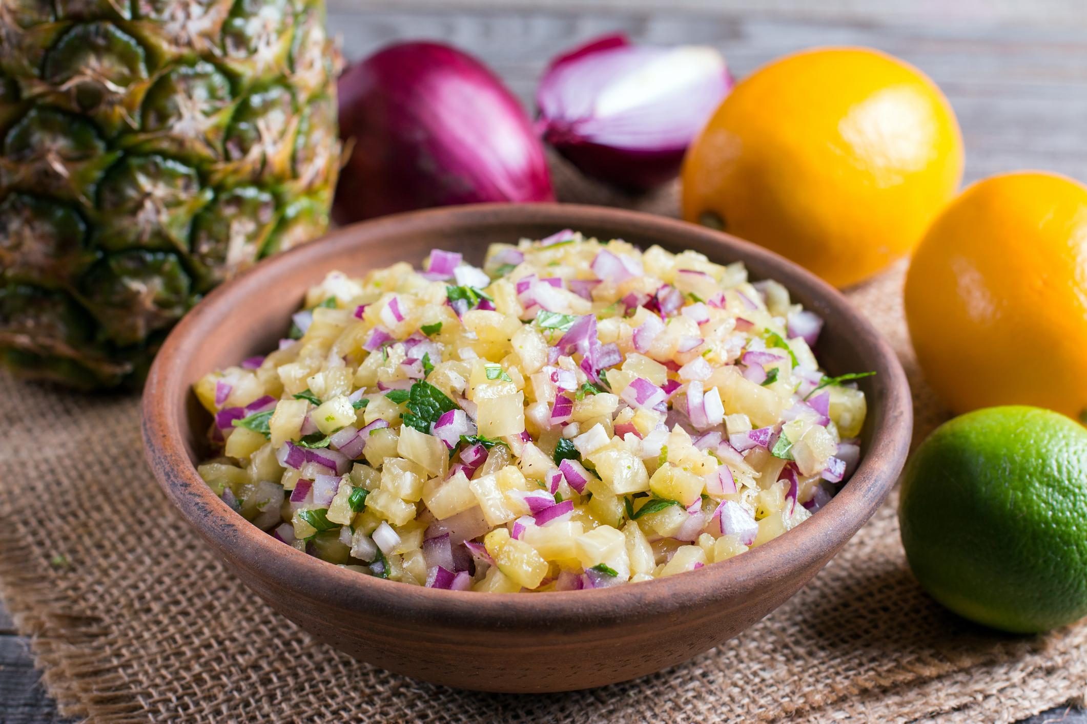 Pineapple mango salsa in a bowl surrounded by the ingredients. 