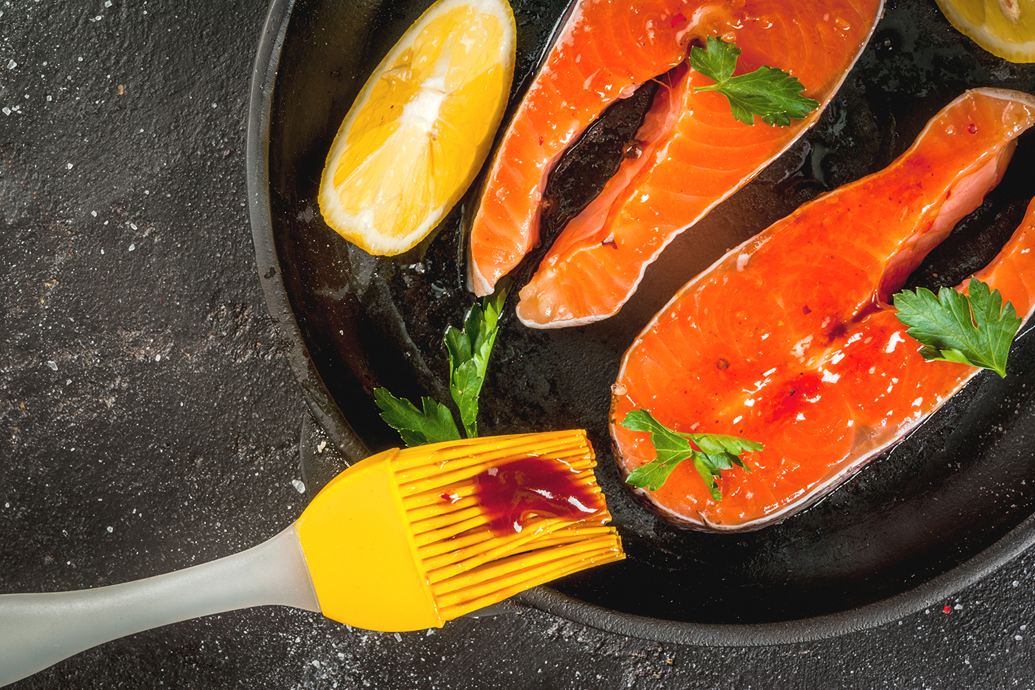 salmon being slathered with sauce for the grill