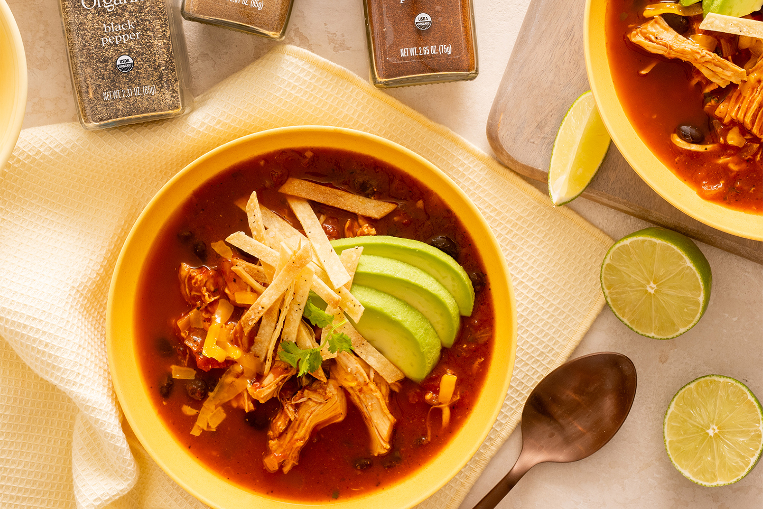 a bowl of spicy red chicken soup with avocado