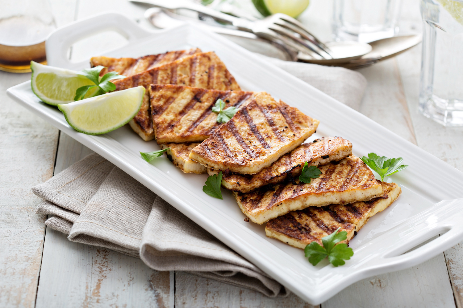 grilled tofu on a plate with limes and cilantro