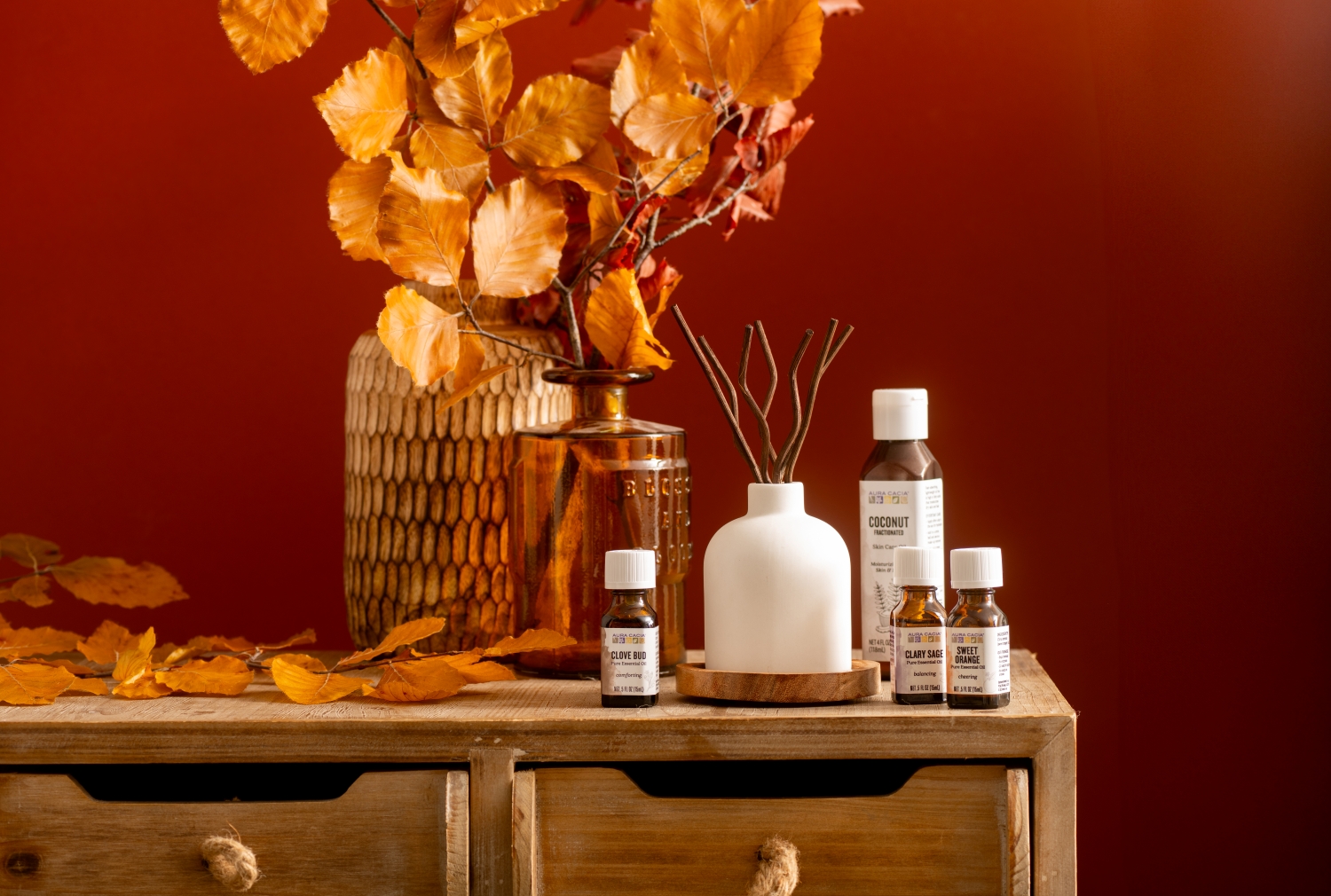 wooden dresser with vase full of fall branches, essential oils and reed diffuser