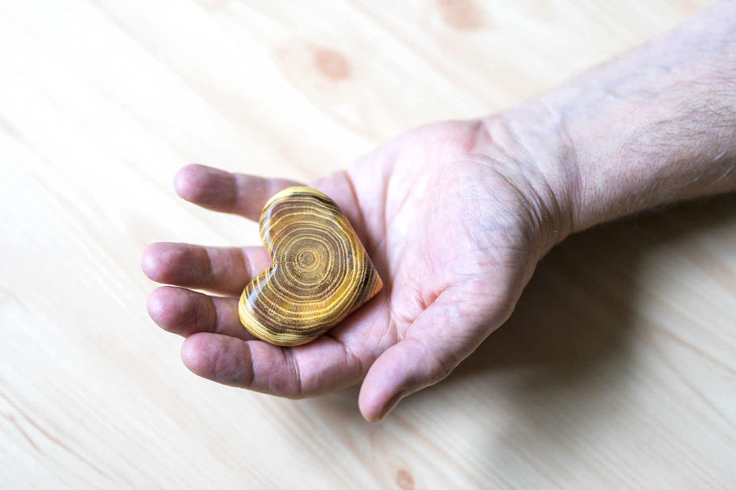 an old man offering a heart carved out of wood