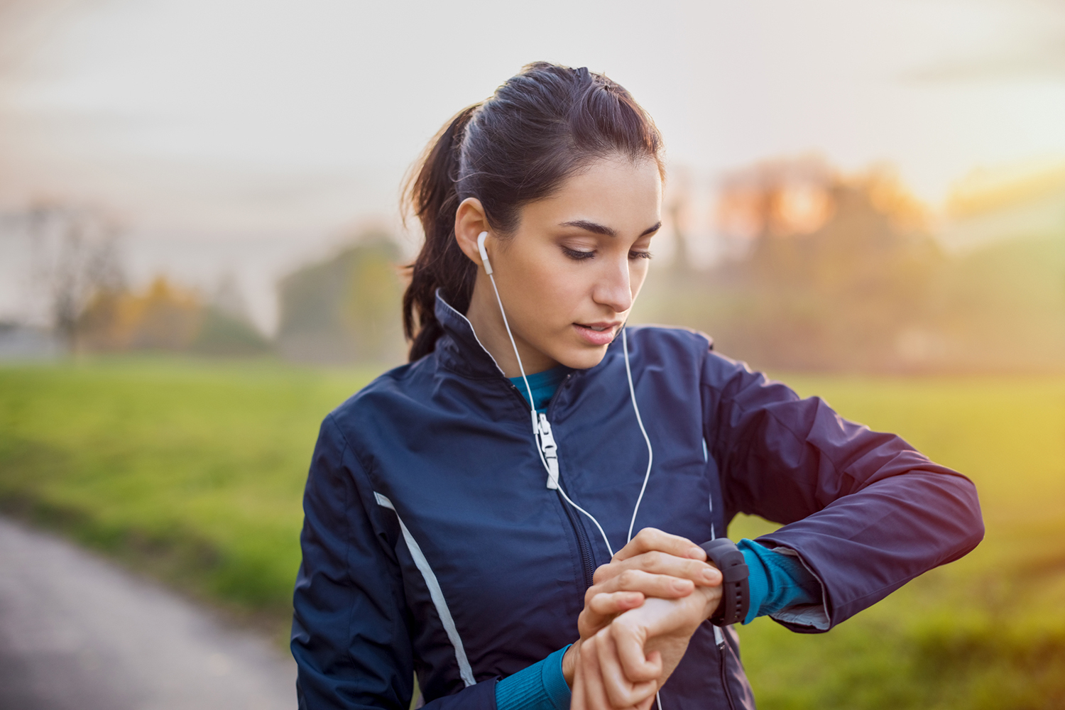a woman walking the park, checking her smartwatch