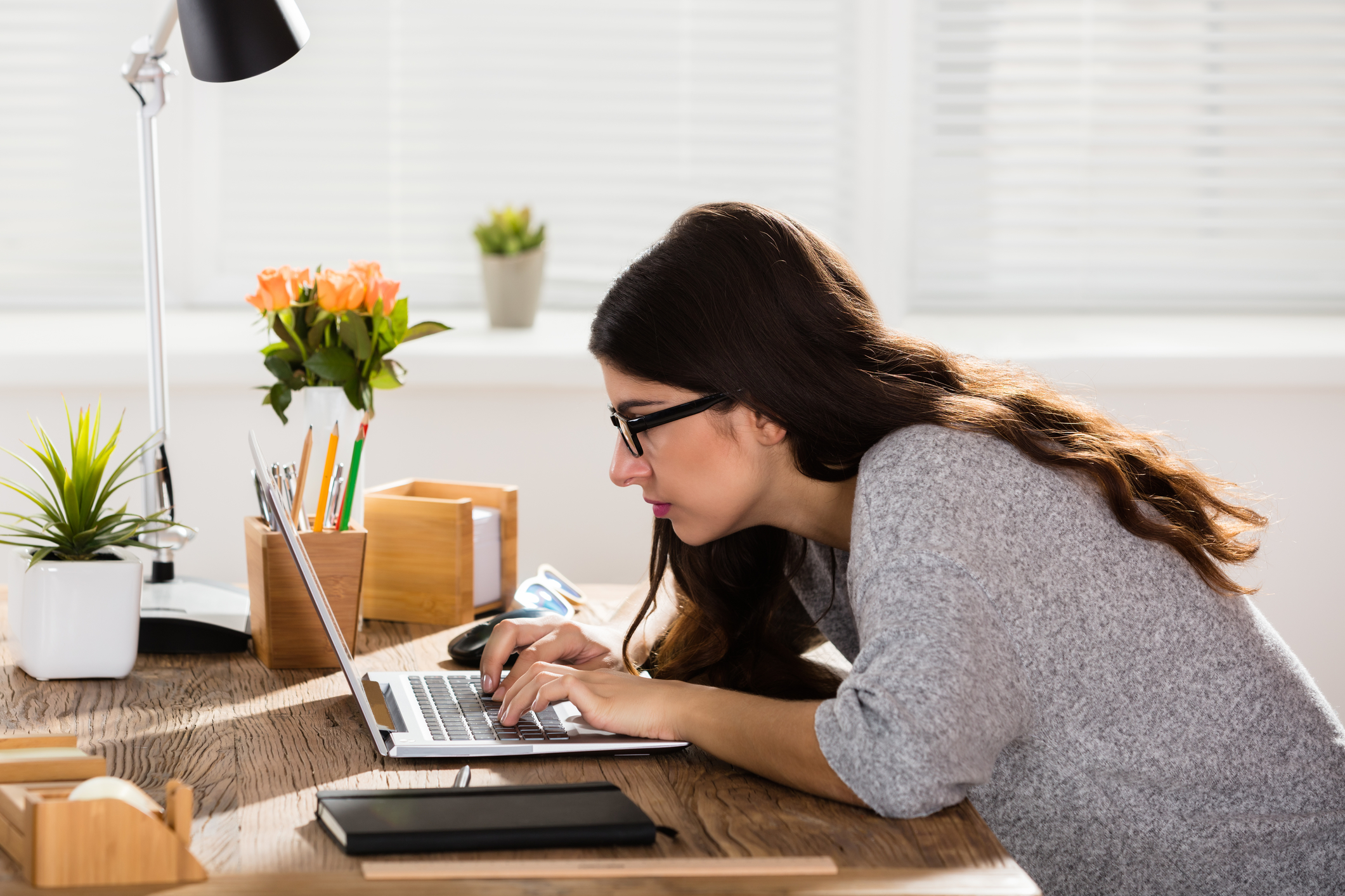 A woman on her computer hunched over working.