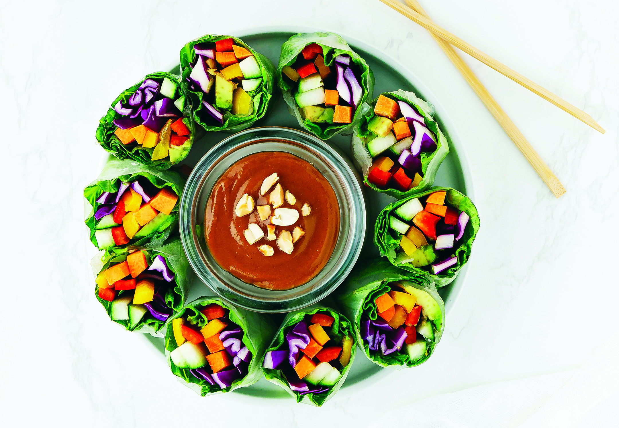 Colorful veggies wrapped in lettuce, positioned vertically around a dish of hoisin sauce.