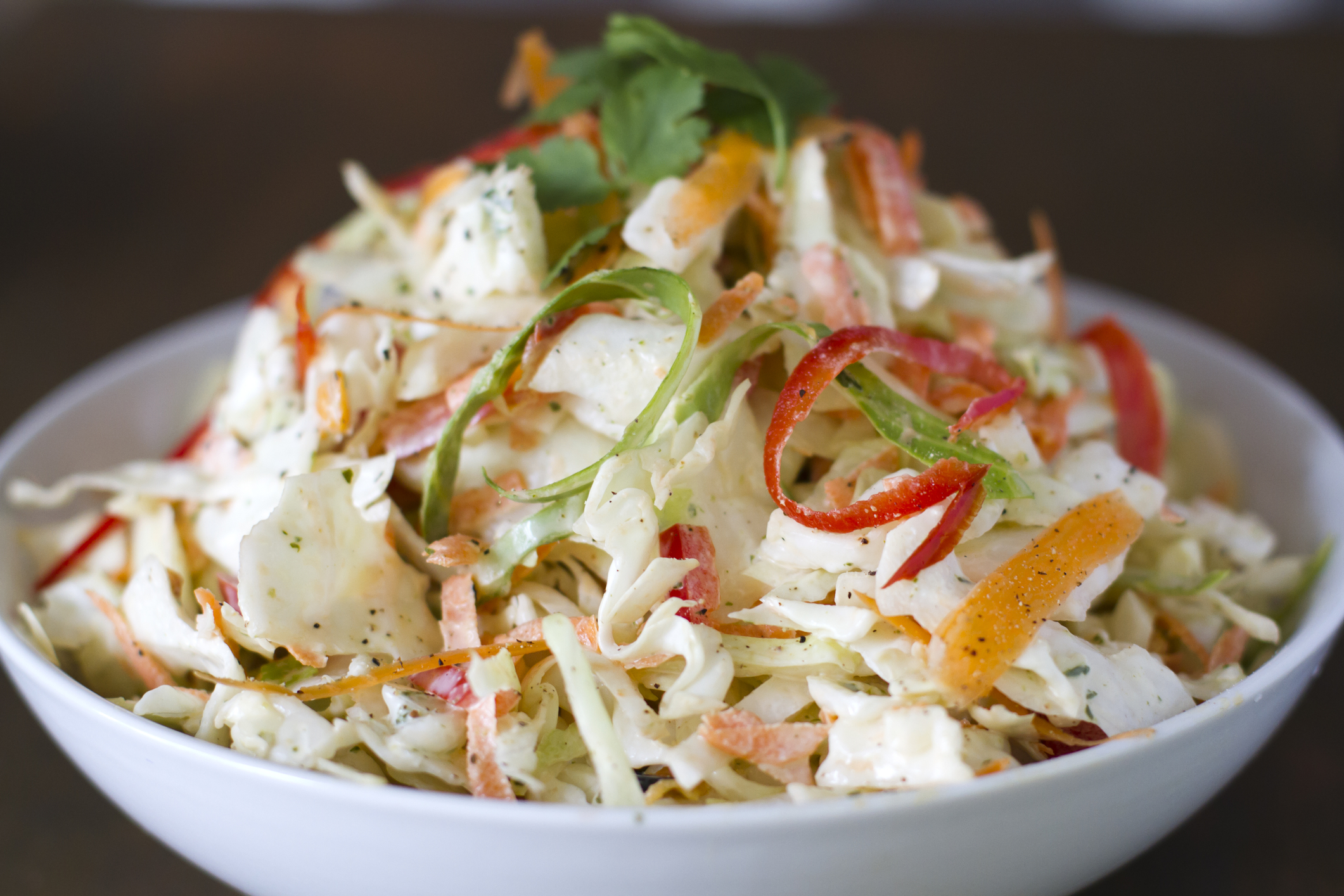 White bowl of green cabbage and bell pepper cole slaw.