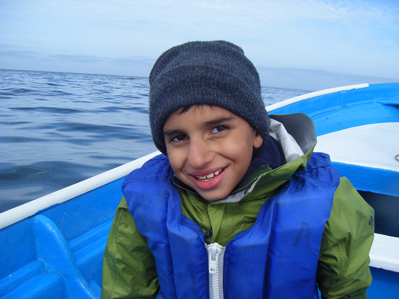 A smiling boy on a boat in the ocean.