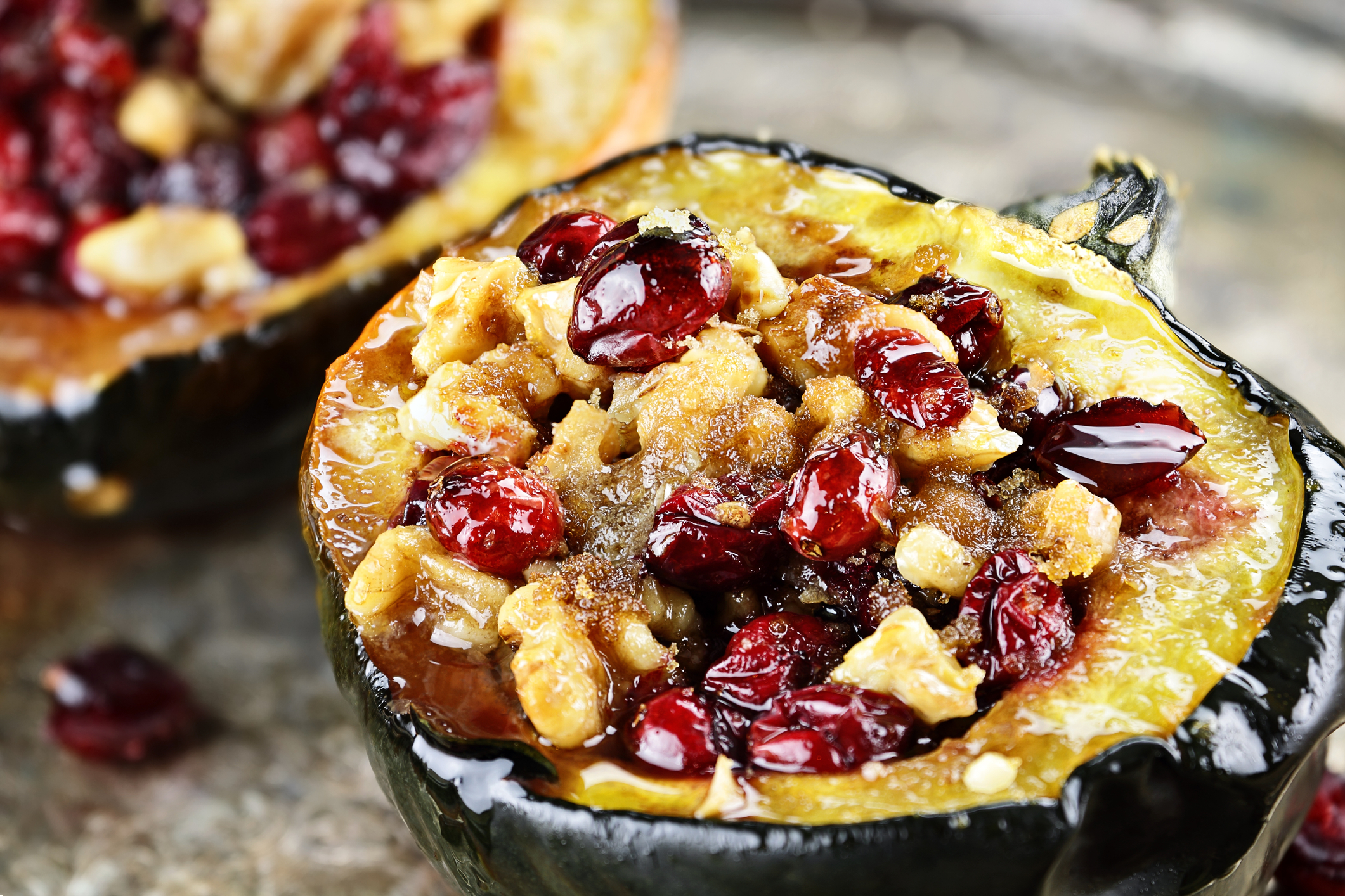 An acorn squash half stuffed with meat, dried cranberries, and walnuts.