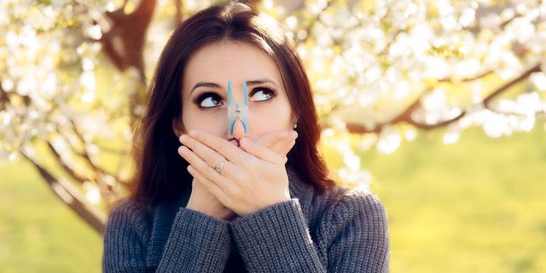 a woman pinching her nose and covering her mouth to avoid seasonal allergies