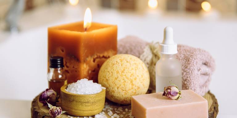 natural body care ingredients and candles next to a warm bath