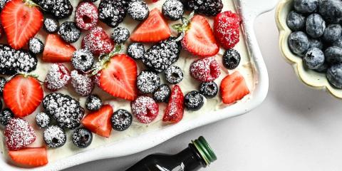 berries on tiramisu with powdered sugar on them also bottle of vanilla extract
