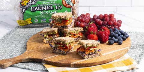sandwich cut up on plate with fruit and bread behind it