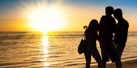 a group of friends watching a sunset on the beach