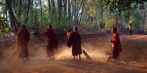 young monks sweeping the dirt yard