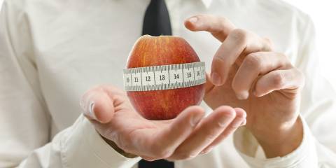 An apple being measured for diameter