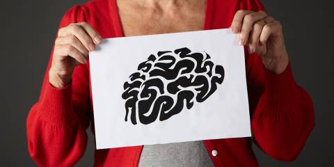 An older woman holding up an illustration of a brain