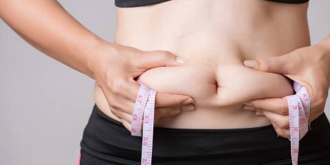 a healthy woman squeezing her excess tummy fat