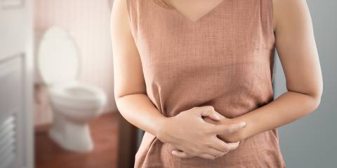 A woman outside the bathroom with bowel cramps from bloating