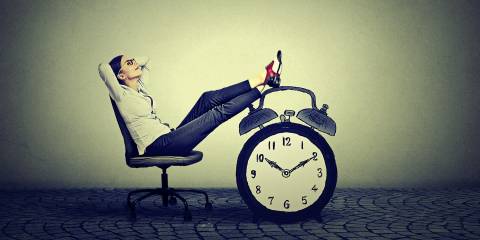 Woman relaxing on a chair with feet resting on a clock