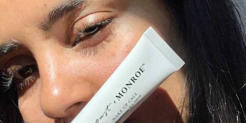 a woman with beautiful eyes holding up a tube of serum