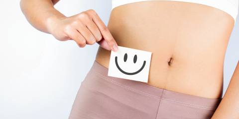 a woman holding a smiley face over her abdomen