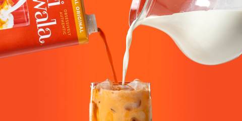 Milk and thai tea being poured into a glass