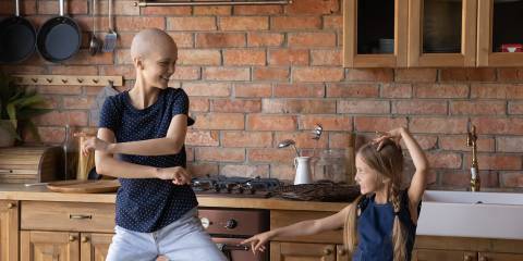 a young woman with cancer, dancing in the kitchen with her daughter