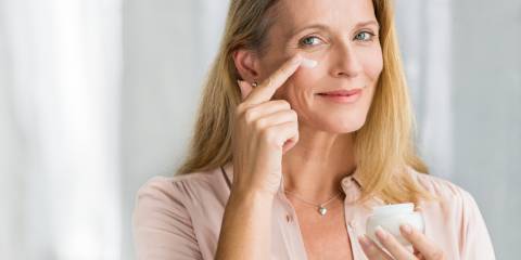 Woman applying anti-aging cream on her face. 