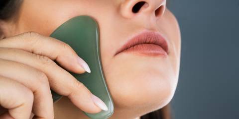 a woman using a gua sha massage tool on her face