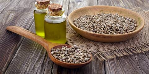 a bowl of hemp seeds and vials of oil