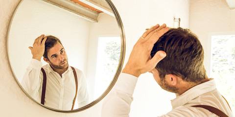Man grooming his hair in front of a mirror.