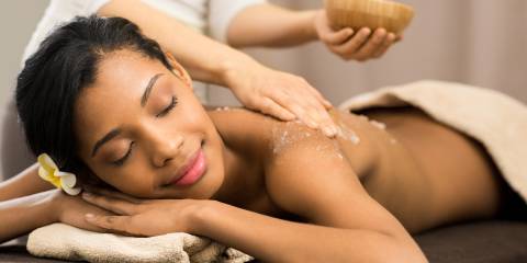a relaxed woman having a scrub applied to her skin