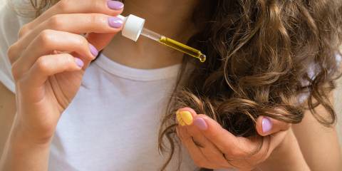 a young woman applying oil to her hair